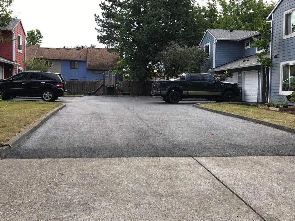 New asphalt driveway blending seamlessly into concrete sidewalk to help illustrate Signs of a Bad Asphalt Job