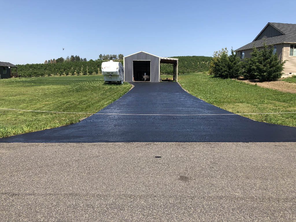 a fresh new asphalt driveway to an outbuilding to help illustrate What Is the Asphalt Paving Process?