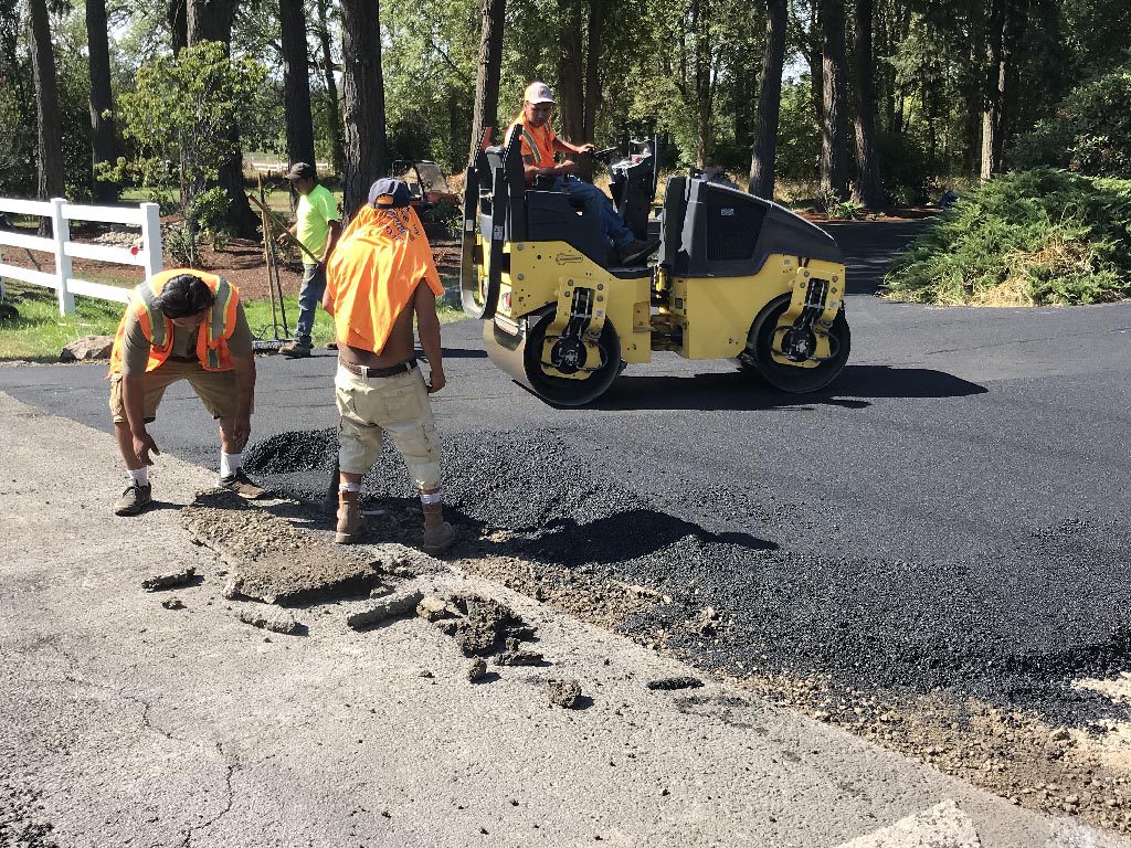 A crew laying new asphalt for a driveway to help illustrate Asphalt Patio and Sidewalk Contractors and What Is the Asphalt Paving Process?