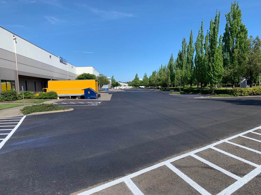 Image of a new asphalt parking lot in a business park too help illustrate commercial asphalt resurfacing and Asphalt vs. Concrete Parking Lot