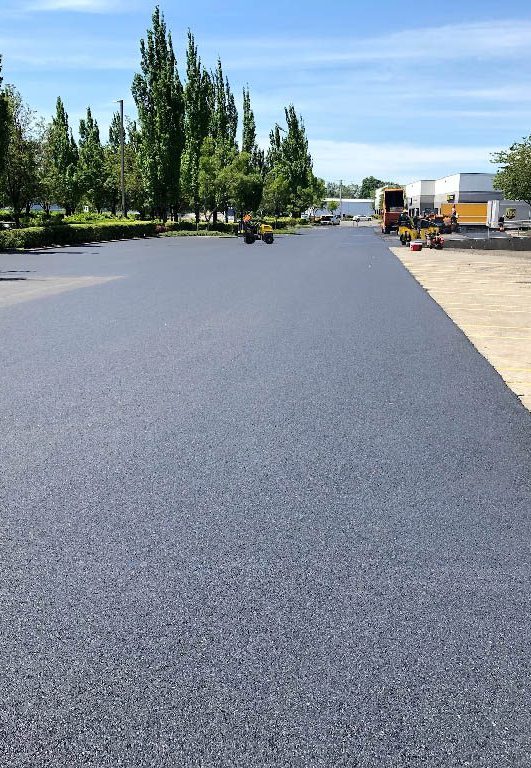 New asphalt parking lot being installed at a loading dock to help illustrate Asphalt vs. Concrete Parking Lot