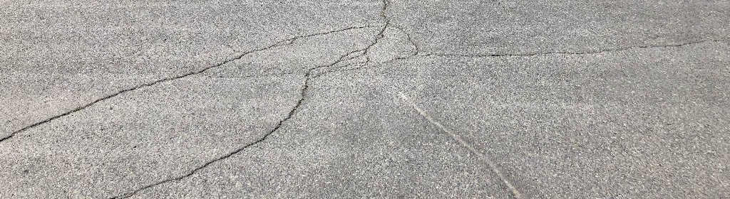 Cracks in an asphalt driveway to help illustrate fix driveway cracks.